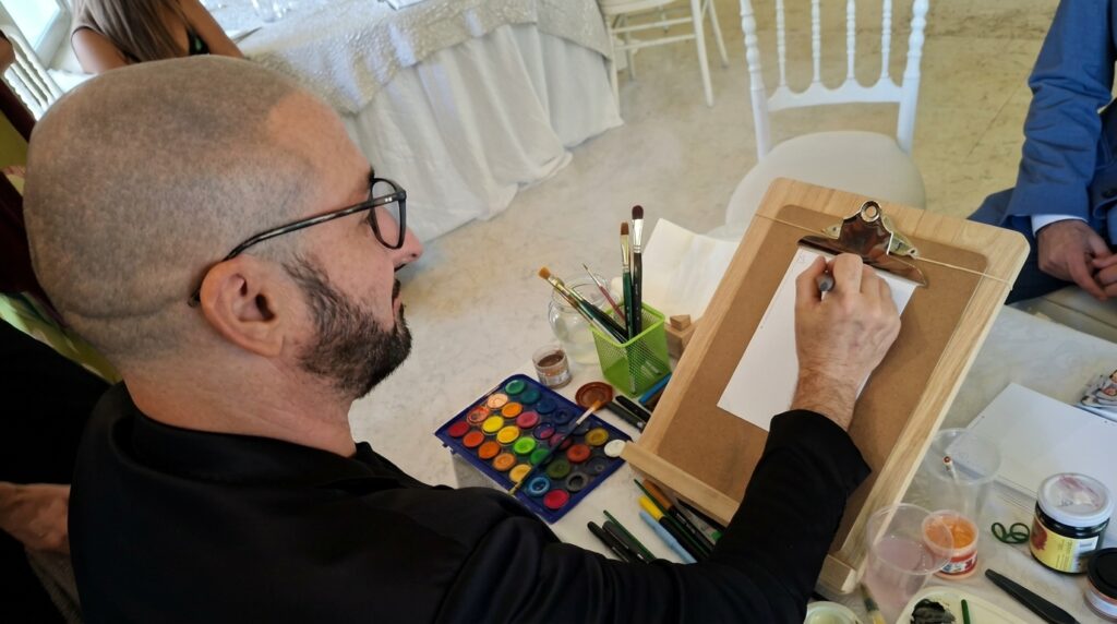 Carmelo de Carlo offre un servizio di Live Sketching per eventi, matrimoni, cerimonie, feste private e aziendali: ritratti ad acquerello e china realizzati dal vivo in 4-6 minuti per ospite, con grafica personalizzata e confezionamento bomboniera. Un'idea originale che unisce intrattenimento artistico e ricordo personalizzato da regalare agli invitati.